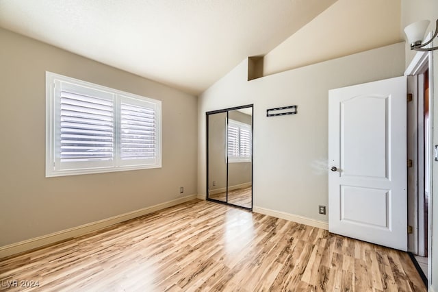 unfurnished bedroom with light wood-type flooring, a closet, and lofted ceiling