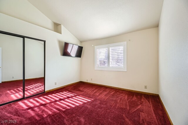 unfurnished bedroom with carpet flooring, vaulted ceiling, and a closet