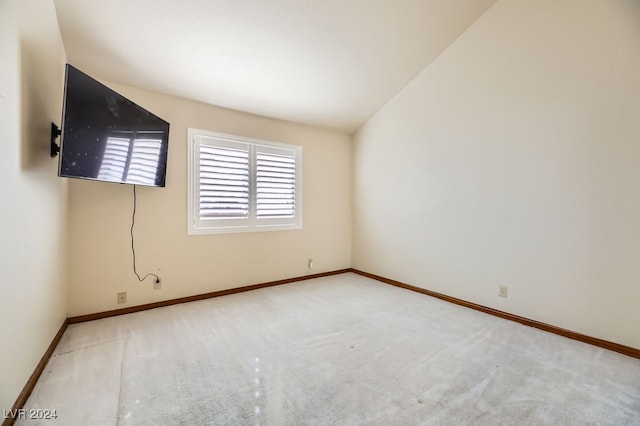 unfurnished room with light colored carpet and lofted ceiling