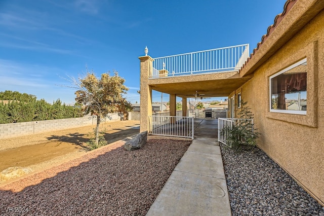 view of yard with ceiling fan and a balcony