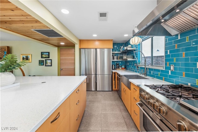 kitchen with island range hood, stainless steel appliances, decorative backsplash, light brown cabinets, and light stone countertops