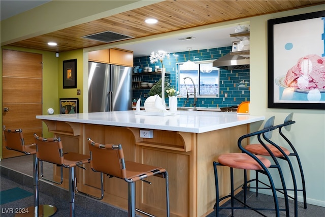 bar with decorative backsplash, wood ceiling, stainless steel refrigerator, and range hood