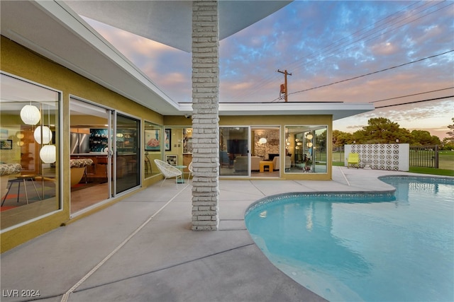 pool at dusk featuring a patio