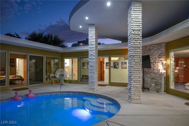 pool at dusk with a patio area