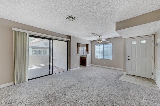 interior space with ceiling fan, sink, light carpet, and a textured ceiling