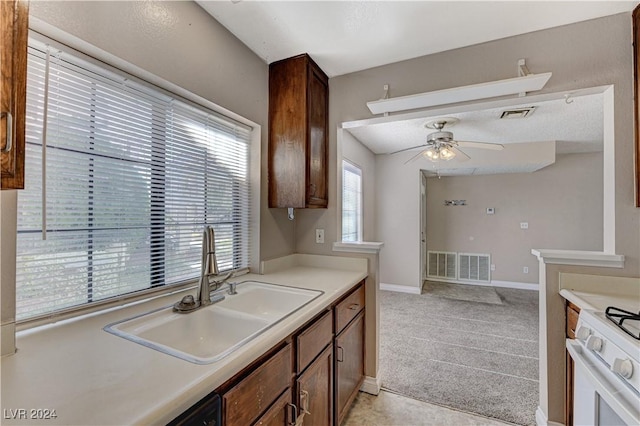 kitchen with sink, light colored carpet, ceiling fan, and white gas stove