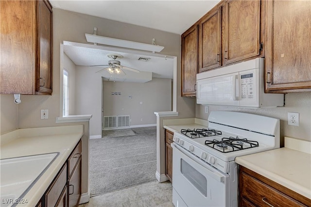 kitchen featuring ceiling fan, sink, light carpet, and white appliances