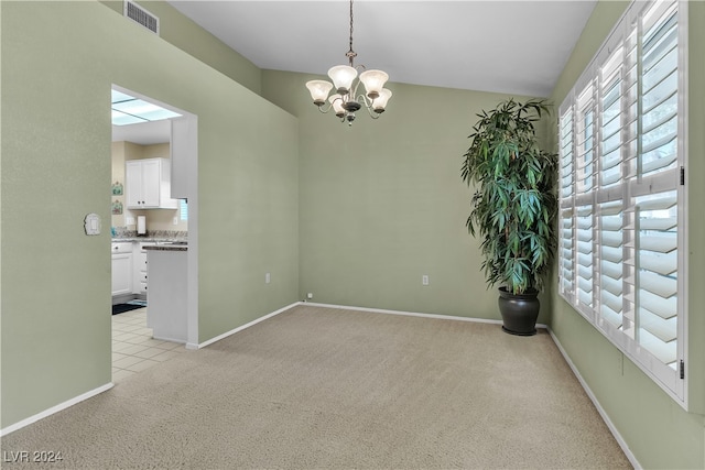 carpeted spare room featuring a chandelier