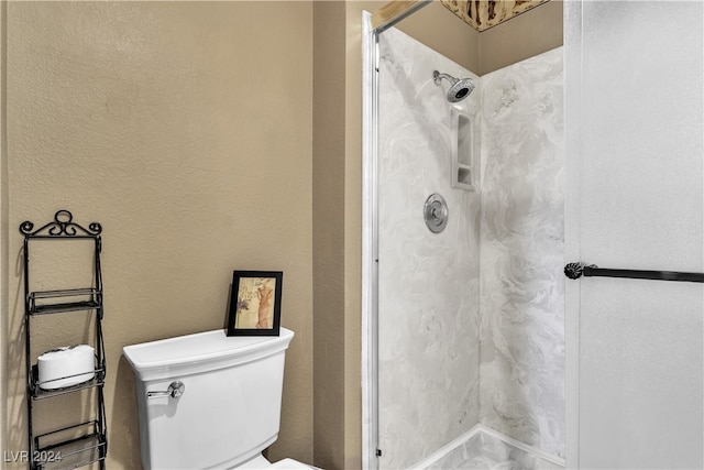 bathroom featuring tiled shower and toilet