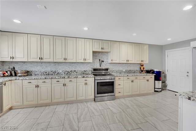 kitchen with backsplash, gas stove, cream cabinetry, and light stone counters