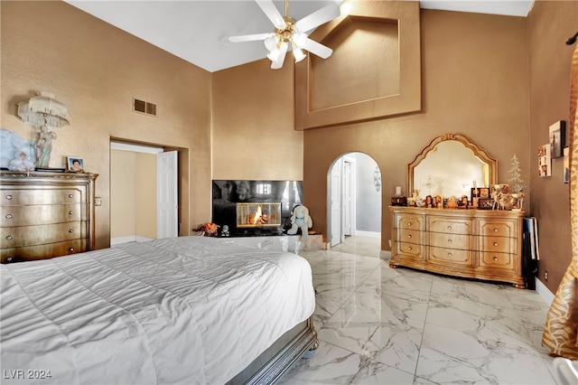 bedroom featuring ceiling fan, high vaulted ceiling, and a multi sided fireplace