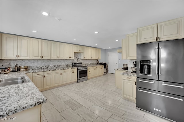 kitchen with light stone counters, appliances with stainless steel finishes, and cream cabinetry