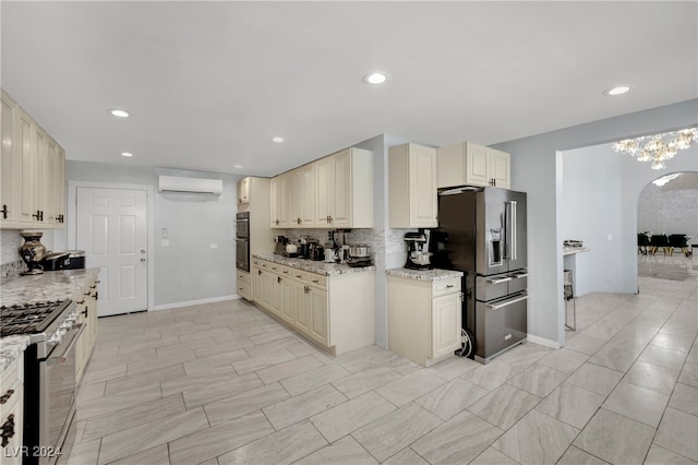 kitchen with tasteful backsplash, light stone countertops, a wall mounted air conditioner, cream cabinetry, and stainless steel appliances