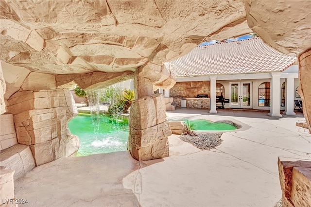 view of swimming pool featuring french doors, pool water feature, and a patio