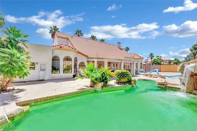 rear view of house with a fenced in pool and a patio