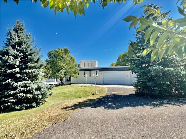 291E Madison Ave, Ely, NV 89301 - view of front facade featuring a garage, a front lawn, driveway, and stucco siding
