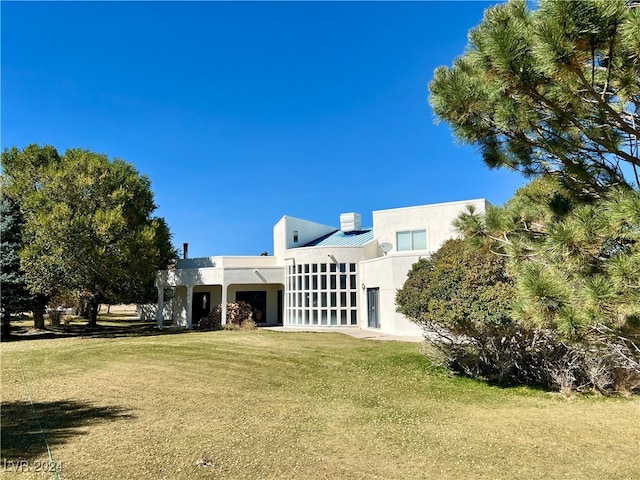 291E Madison Ave, Ely, NV 89301 - back of property featuring stucco siding, a yard, a chimney, and metal roof