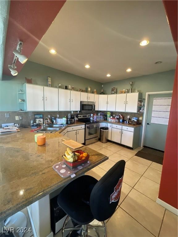 291E Madison Ave, Ely, NV 89301 - kitchen featuring stainless steel appliances, open shelves, a sink, light tile patterned flooring, and white cabinetry