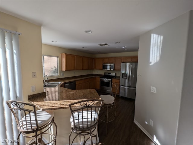 kitchen featuring sink, kitchen peninsula, stainless steel appliances, and dark wood-type flooring