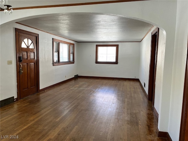 entrance foyer featuring crown molding, a textured ceiling, and dark hardwood / wood-style flooring