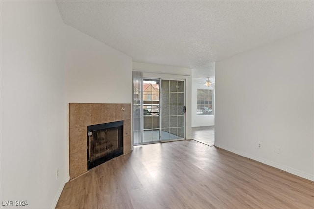 unfurnished living room with a fireplace, a textured ceiling, light hardwood / wood-style flooring, and ceiling fan