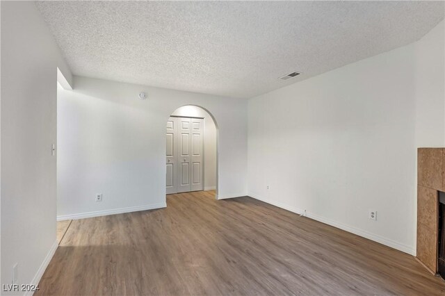 unfurnished living room featuring a fireplace, a textured ceiling, and hardwood / wood-style flooring