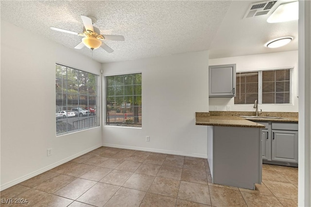 kitchen featuring sink, ceiling fan, gray cabinets, light tile patterned floors, and a textured ceiling