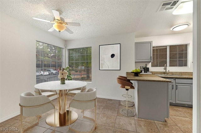 dining room with light tile patterned floors, a textured ceiling, ceiling fan, and sink