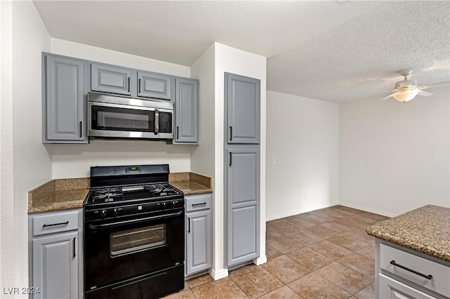 kitchen with gas stove, ceiling fan, dark stone countertops, a textured ceiling, and gray cabinets