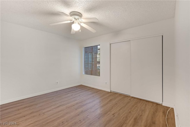 unfurnished bedroom featuring ceiling fan, a closet, wood-type flooring, and a textured ceiling