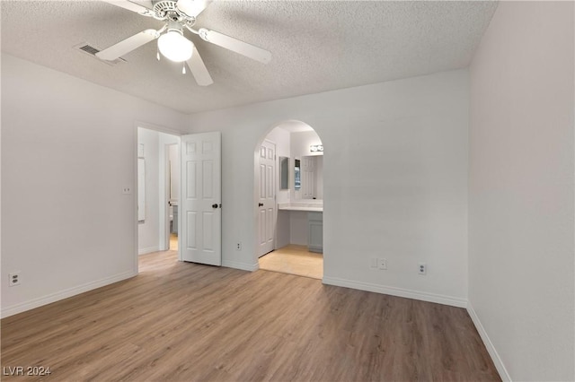 unfurnished bedroom featuring ceiling fan, ensuite bath, a textured ceiling, and light hardwood / wood-style flooring