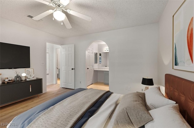 bedroom featuring connected bathroom, ceiling fan, a textured ceiling, and light wood-type flooring