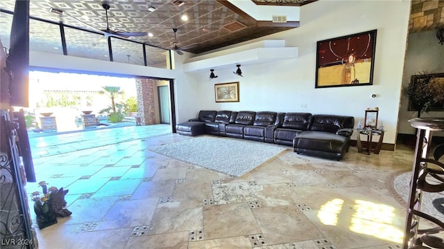 living area featuring stone tile floors, baseboards, visible vents, and a towering ceiling