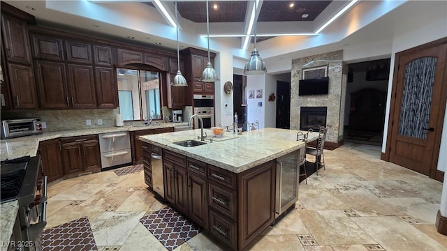 kitchen featuring decorative backsplash, stone tile floors, light stone counters, and a sink