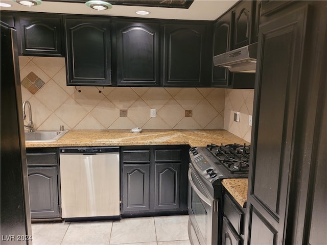 kitchen featuring light stone countertops, tasteful backsplash, stainless steel appliances, sink, and light tile patterned flooring