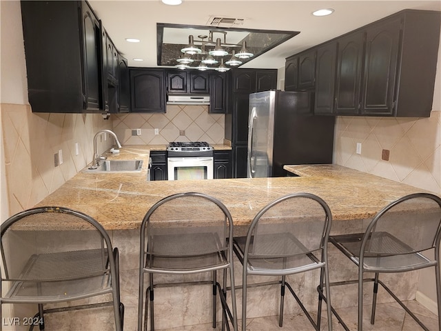 kitchen with white range with gas stovetop, kitchen peninsula, stainless steel refrigerator, and sink