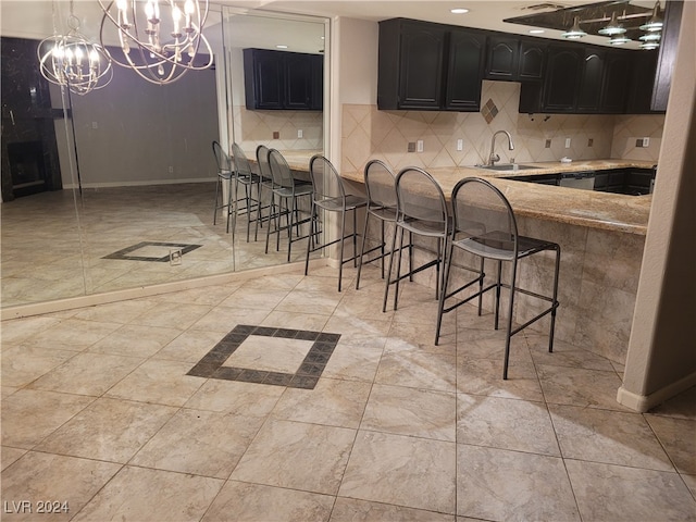 kitchen featuring a kitchen breakfast bar, pendant lighting, a notable chandelier, and sink