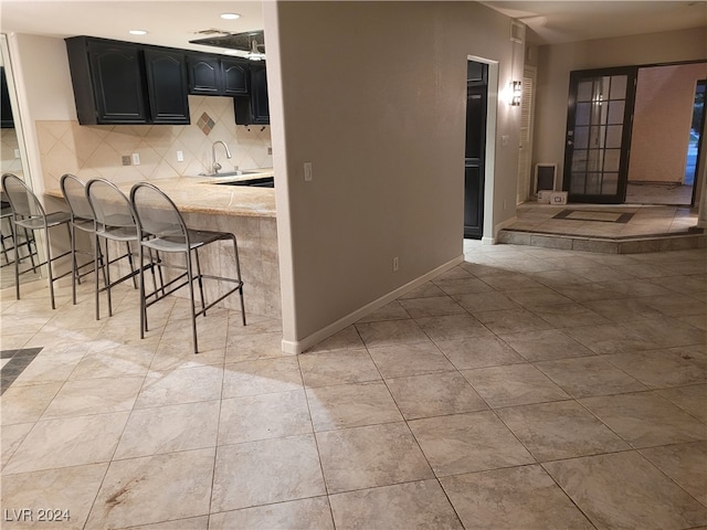 kitchen with a breakfast bar area, kitchen peninsula, sink, and backsplash