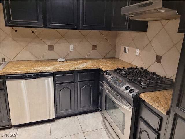 kitchen featuring decorative backsplash, light stone countertops, light tile patterned flooring, and appliances with stainless steel finishes