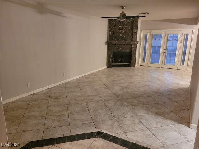 unfurnished living room featuring tile patterned floors, ceiling fan, a fireplace, and french doors