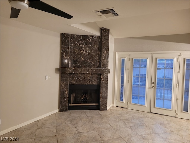 unfurnished living room with ceiling fan, a premium fireplace, light tile patterned floors, and french doors