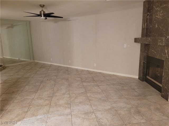 unfurnished living room featuring ceiling fan, a high end fireplace, and light tile patterned floors