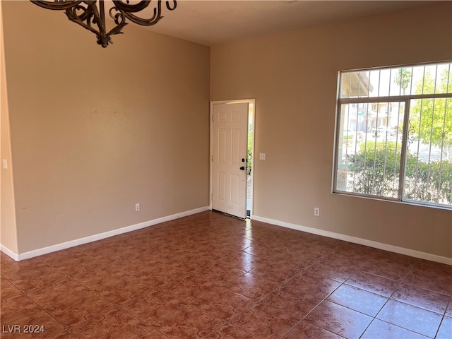 tiled empty room featuring a notable chandelier