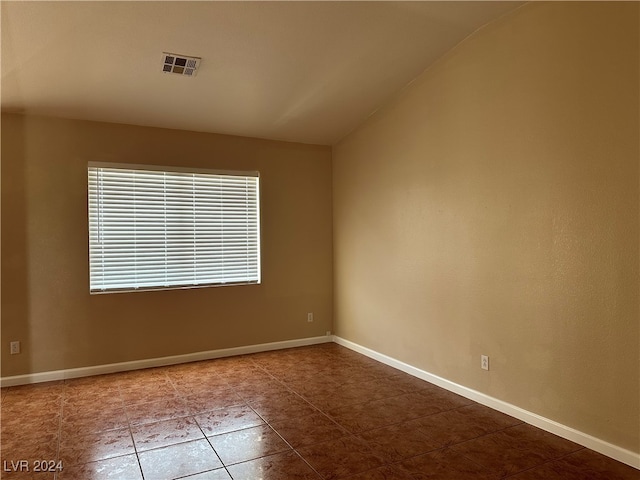 spare room featuring tile patterned floors and lofted ceiling