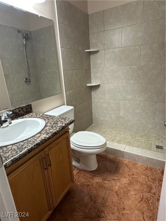 bathroom with vanity, toilet, tile patterned floors, and a tile shower