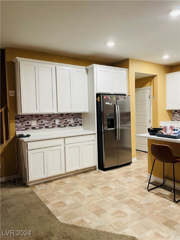 kitchen with white cabinetry, light carpet, tasteful backsplash, and stainless steel refrigerator with ice dispenser