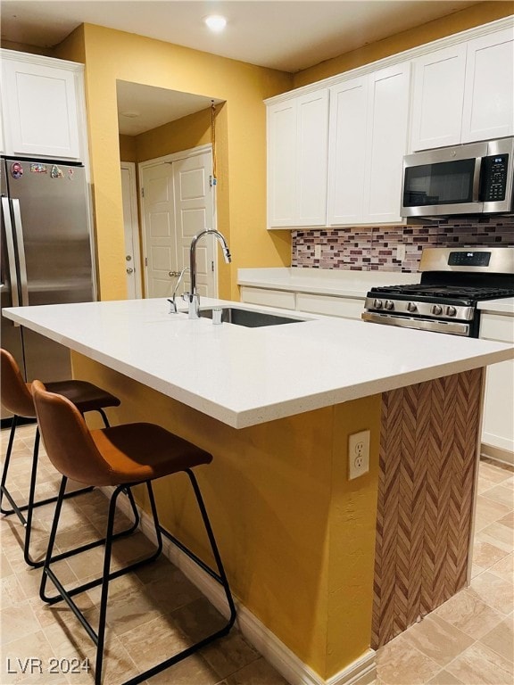 kitchen featuring sink, an island with sink, stainless steel appliances, and white cabinets