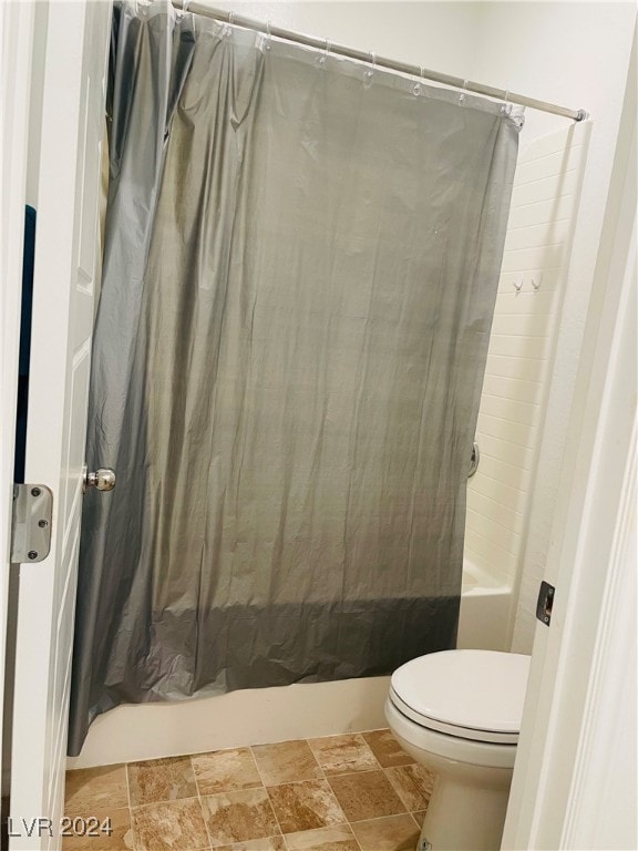 bathroom featuring toilet and shower / tub combo with curtain