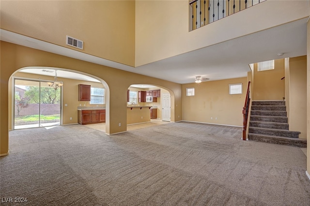 unfurnished living room with a towering ceiling and light colored carpet