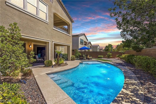 pool at dusk featuring a patio area